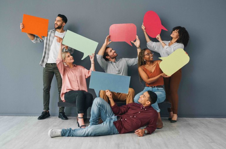 Full length shot of a young and diverse group of businesspeople holding up blank placards in the shape of speech bubbles against a grey background in studio